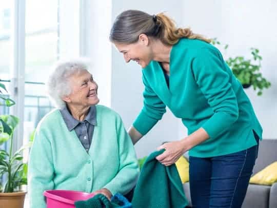 Eine lächelnde Alltagsfee hilft einer Seniorin im Haushalt in Stolberg.