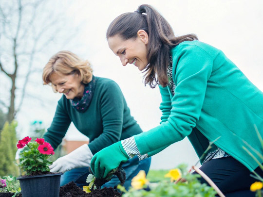 Eine Alltagsfee aus Warendorf hilft einer Frau bei der Gartenarbeit.